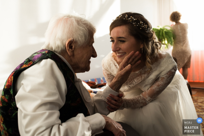 Die Braut nimmt den Arm eines Mannes, als er ihr Gesicht auf diesem Foto eines Hochzeitsfotografen aus Malopolskie, Polen, berührt.