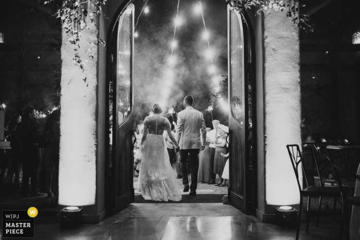 Foto por: <a href="https://www.wpja.com/contests/2017-tri3-photography-competition/send-offdeparture/2123771"> Philip Thomas - Estados Unidos </a> Foto en blanco y negro de la novia y el novio saliendo mientras se toman de la mano, tomada desde atrás por un fotógrafo de bodas de San Antonio, TX.