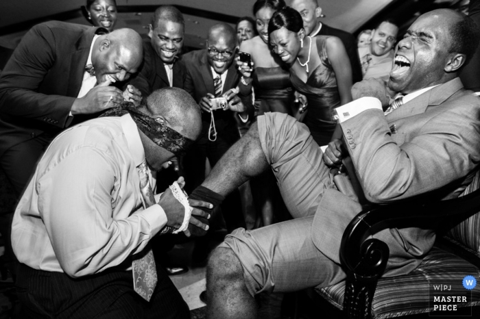 Photo by: <a href="https://www.wpja.com/contests/2012-q1-contest/reception/872876">Arek Kadzielawski - United States</a> New York City - Metro Wedding Photographer | Image contains: groom blindfold men joke funny reception