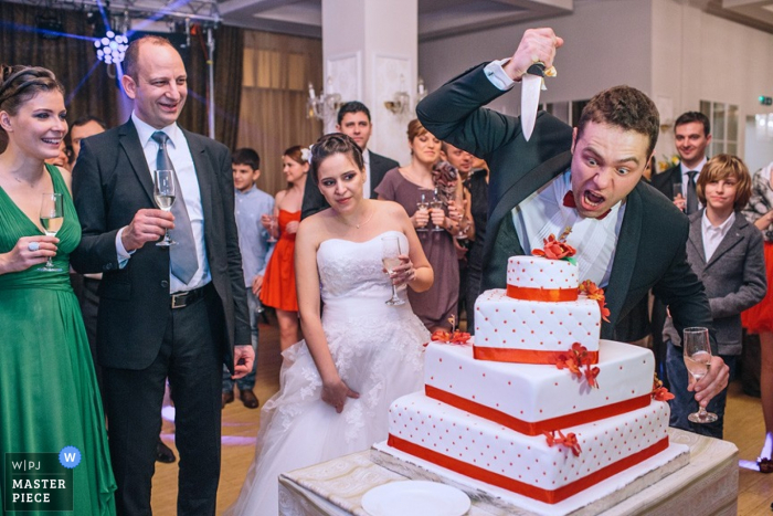 Photo by: <a href="https://www.wpja.com/contests/2013-q1-contest/reception/1140126">Ivo Popov - Belgium</a> Brussels wedding photographer captured this humorous photo of the groom pretending to stab the wedding cake while the bride stands nearby, looking concerned