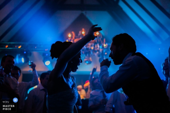 Paraná wedding photographer captured this photo of the bride and groom dancing as blue lights shine behind them