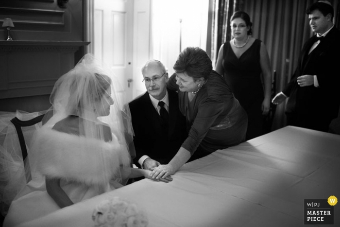 El fotógrafo de bodas de Atlanta capturó esta imagen emocional en blanco y negro de la novia hablando con sus padres antes de la ceremonia mientras se tomaban de las manos