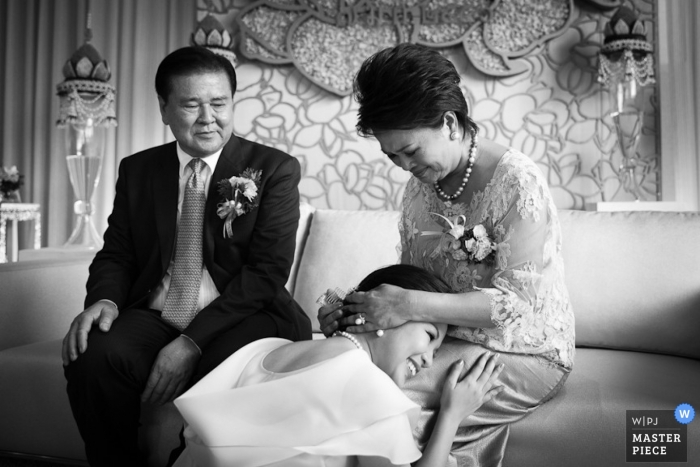 Bangkok wedding photographer captured this black and white photo of the bride kneeling before her parents before her wedding ceremony