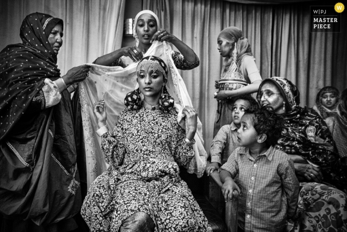 Photo by: <a href="https://www.wpja.com/contests/2013-q1-contest/full-frame-black-and-white/1143716">Christophe Viseux - Canada</a> Toronto wedding photography in black and white of the bride getting ready before the ceremony as many family members watched around her