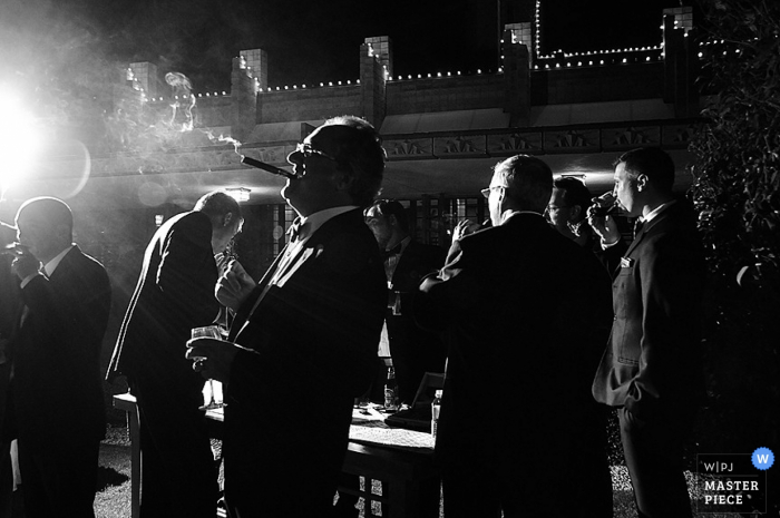 Phoenix wedding photographer | black and white photo of the groomsmen enjoying cigars on the patio