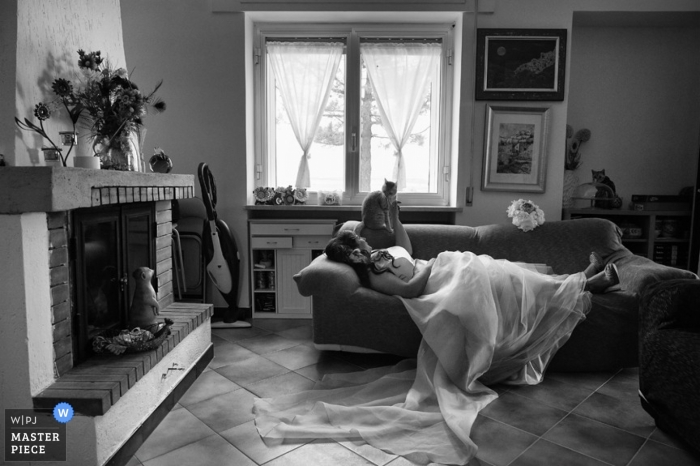 Photo by: <a href="https://www.wpja.com/contests/2013-q2-contest/animals/1174521">Pietro Moliterni - Italy</a> Italy Wedding Photography | Image contains: bride, cat, couch, sofa, home, rest, bouquet, fireplace