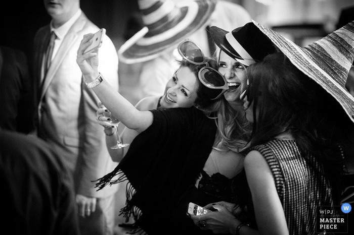 Photo: <a href="https://www.wpja.com/contests/2013-q2-contest/reception/1198921"> Martin Beddall - Royaume-Uni </a> Photographie de mariage West Sussex | L'image contient: noir, blanc, invités au mariage, réception, sombrero, selfie