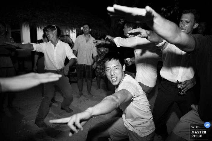 Photographie de mariage documentaire à Bangkok | L'image contient: invités au mariage, noir, blanc, danse, bras