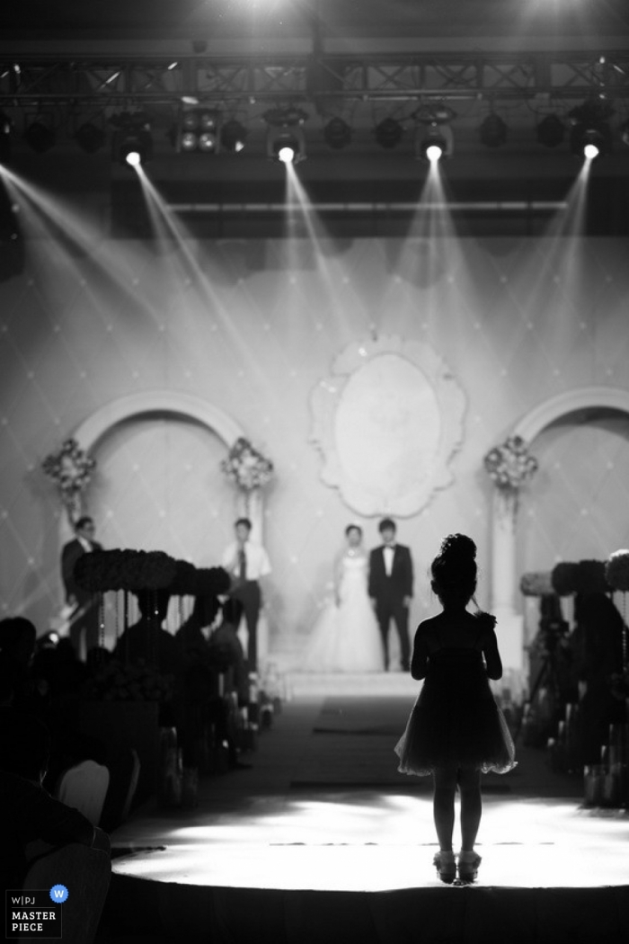 Foto: <a href="https://www.wpja.com/contests/2013-q2-contest/kids-being-kids/1175736"> Lin Zhao - China </a> Fotógrafo de bodas en Shanghai | La imagen contiene: ceremonia, niña de las flores, luces, negro, blanco, bancos