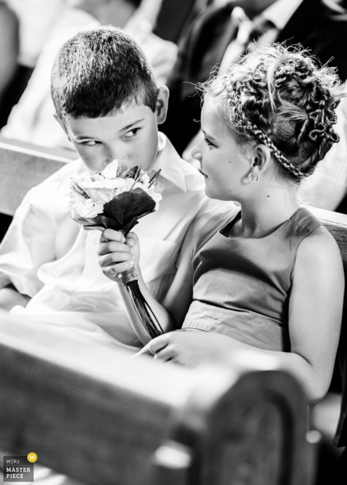 Foto de: <a href="https://www.wpja.com/contests/2013-q2-contest/kids-being-kids/1208311"> Alexandre Bourguet - Suiza </a> Suiza Documental Fotógrafo de bodas | La imagen contiene: niña de las flores, niño, flores, bancos, ceremonia, negro, blanco