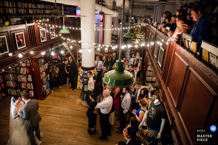 Fotógrafo de bodas documental de Manhattan | La imagen contiene: recepción, invitados a la boda, libros en el interior, luces.