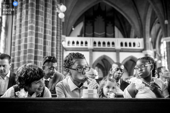 Dentro de una iglesia de Zuid Holland, los niños se toman un momento para tomar un refrigerio mientras esperan la fiesta de bodas.