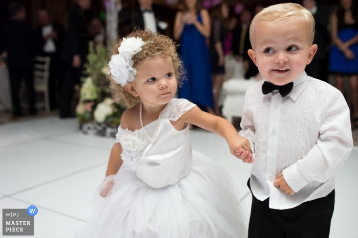 A determined young flower girl steps onto the dance floor with her page boy partner in this keepsake wedding image for parents