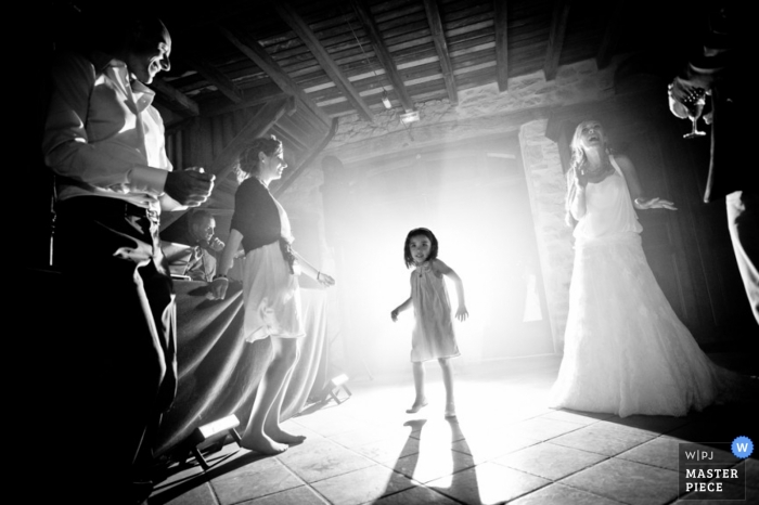 A young Landes wedding guest dances in the DJs lights as a Nouvelle-Aquitaine bride looks on in this BW photo