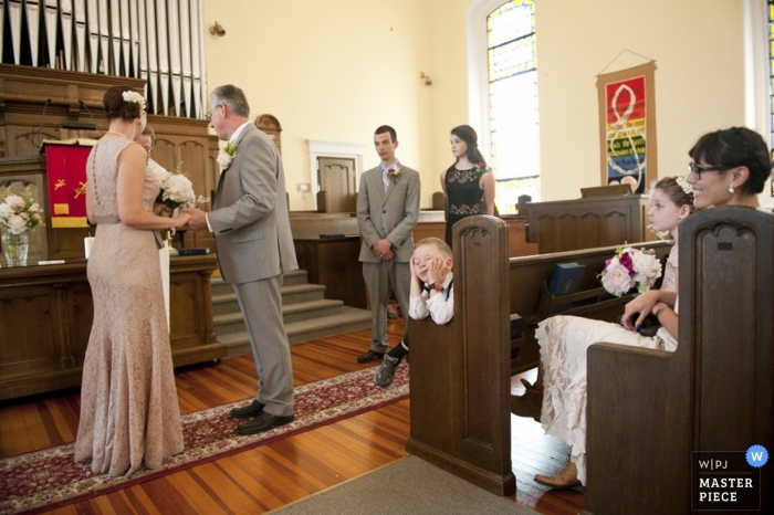 Eine Braut in einem nackten Kleid und ihr Bräutigam tauschen in einer Kirche in New Jersey in einem traditionellen Bild ihr Eheversprechen