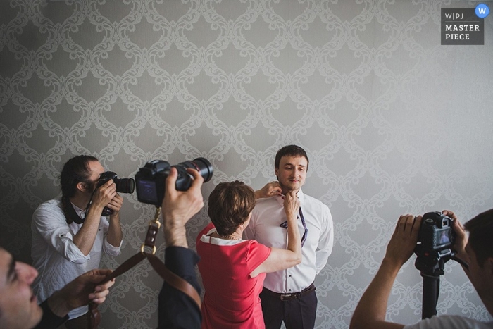 Sint-Petersburg bruiloft paparazzi foto terwijl de bruidegom zich klaarmaakt in een kamer met zilver behang in Rusland