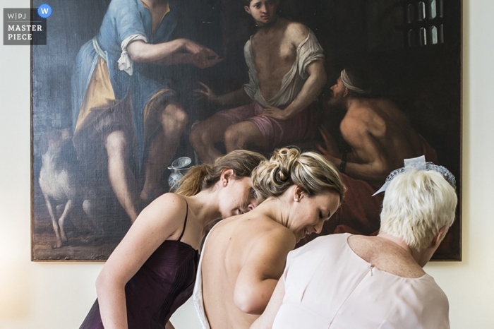 A Venice bride has some help getting ready in Veneto with a Renaissance painting serving as a striking backdrop