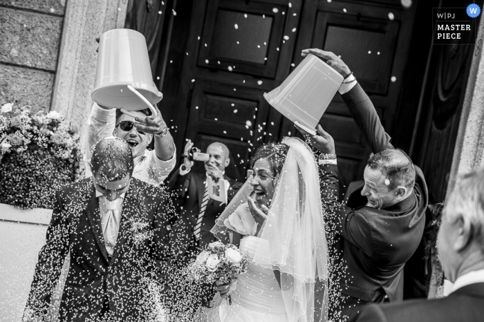 Foto door: <a href="https://www.wpja.com/contests/2014-q3-photography-contest/ceremony/1475511"> Luigi Rota - Italië </a> Lecco Wedding Fotojournalistiek | Afbeelding bevat: zwart en wit, bruid, bruidegom, het verlaten van de ceremonie, confetti, sluier, boeket, kerk, bruiloftsgasten
