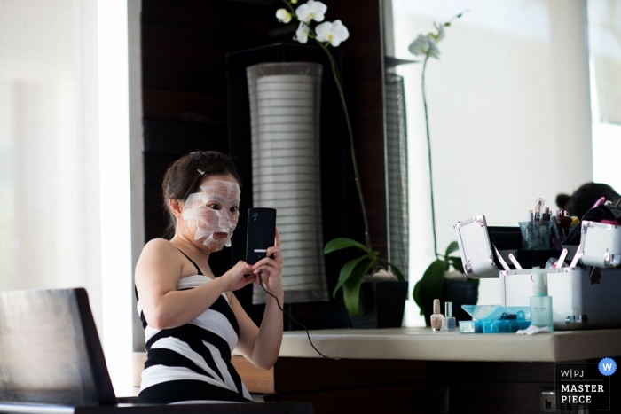 Photo by: <a href="https://www.wpja.com/contests/2014-q3-photography-contest/getting-ready/1505751">Adi Susanto - Los Angeles California Los Angeles Documentary Wedding Photographer | Image contains: getting ready, face mask, selfie hotel room, bride, flowers