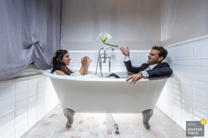 Venice wedding photographer shoots a portrait of the bride and groom relaxing, fully dressed, in a bathtub