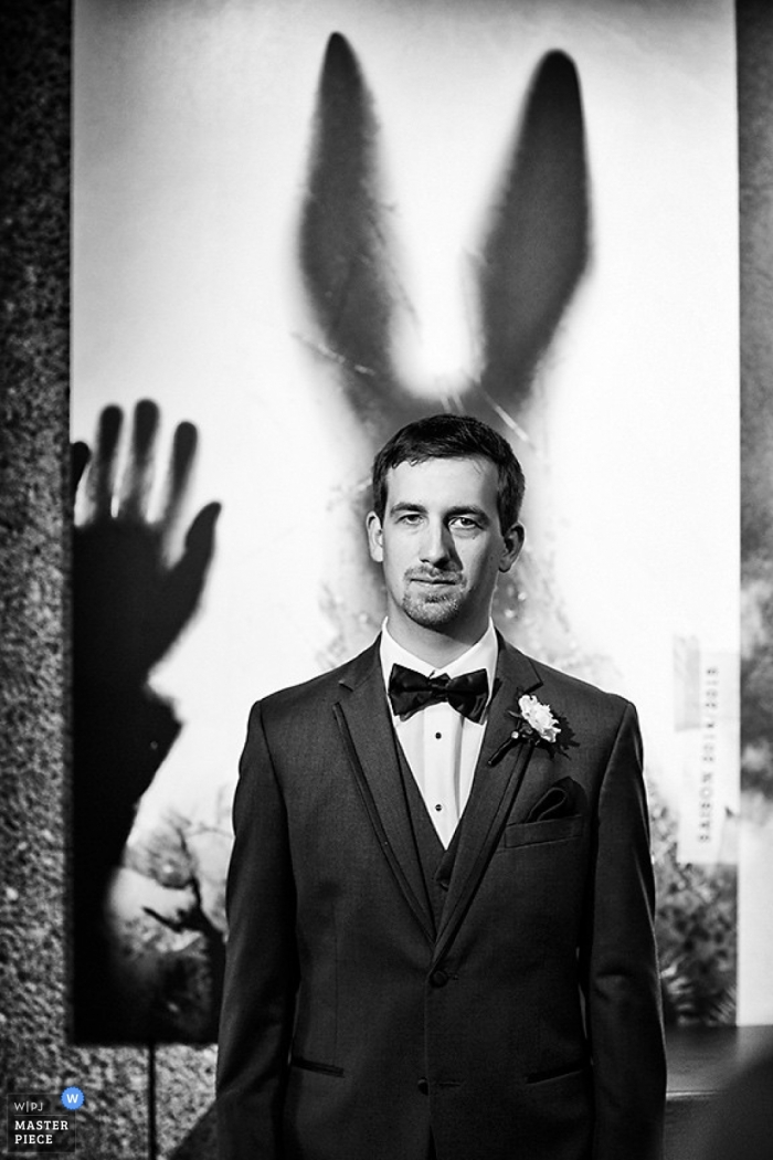 Ottawa wedding photographer created this unique portrait of the groom standing in front a canvas that appears to be giving him ears