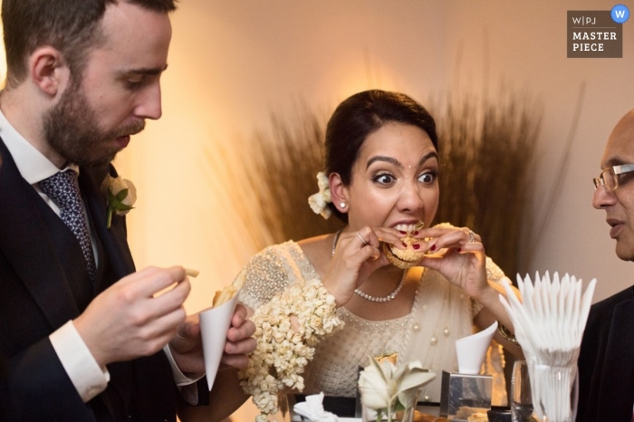 Der Londoner Hochzeitsfotograf hat dieses Foto aufgenommen, auf dem die Braut beim Hochzeitsempfang eine Vorspeise genießt