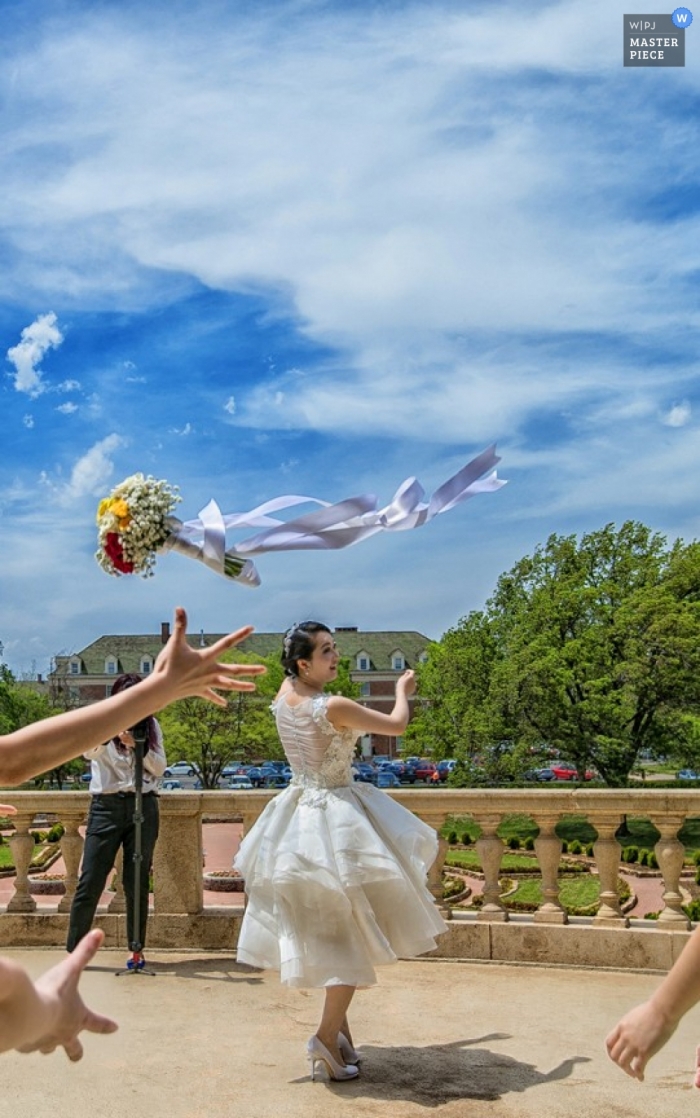 Fotograf ślubny Tianjin kręci akcję panny młodej rzucającej bukiet pod piękne błękitne niebo