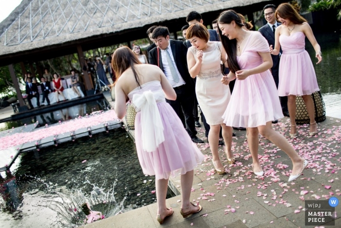 Bali wedding photographer captured this photo of a wedding bouquet falling into a pool at the reception