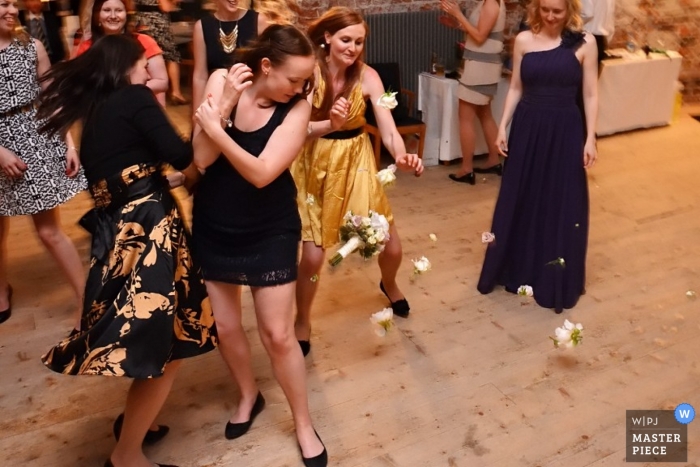 Helsinki wedding photographer captured this photo of some wedding guests running towards and other guests dodging the tossed bouquet during the wedding reception
