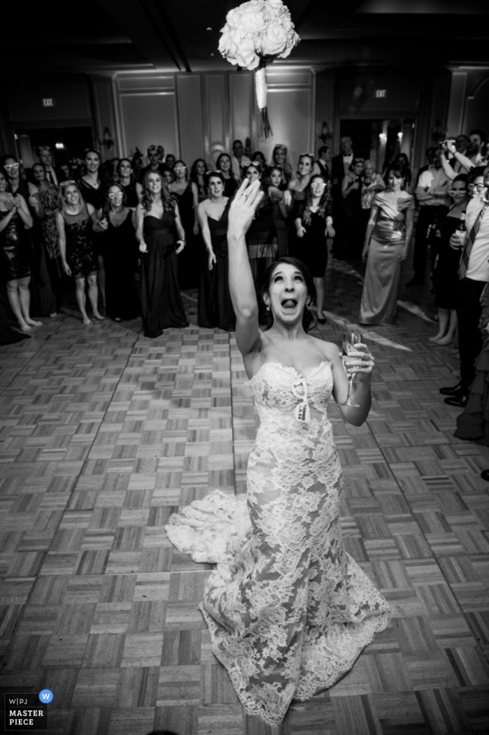 Il fotografo di matrimoni di Houston congela l'azione in questa immagine in bianco e nero della sposa che lancia il suo bouquet al ricevimento di nozze