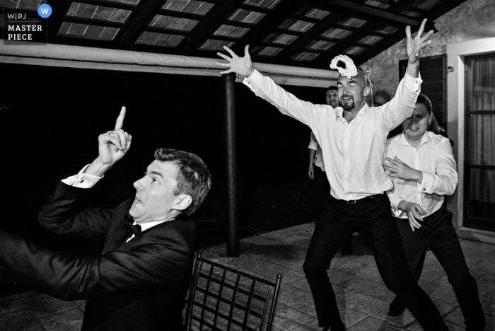 Ljubljana wedding photographer caught the action of the groom tossing the garter in this black and white photo of the reception