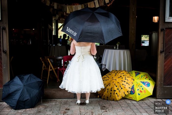 Photo by: <a href="https://www.wpja.com/contests/2014-q4-photography-contest/weather/1563591">Steve Koo - United States</a> Chicago wedding photographer creates a picture of the bride standing at the doorway holding a black umbrella as she waits to go in