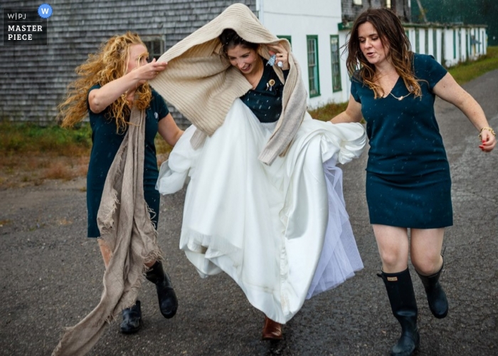 Photo by: <a href="https://www.wpja.com/contests/2014-q4-photography-contest/weather/1568976">Ben Benvie - Canada</a> Toronto wedding photographer freezes the action in this image of the bride covering her head with a shawl as they rush in the rain to the wedding reception