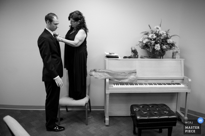 Le photographe de mariage d'Indianapolis a saisi l'instant dans cette photo en noir et blanc de la mère du marié se tenant debout sur une chaise pour l'aider à nouer sa cravate