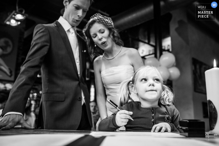 Photo by: <a href="https://www.wpja.com/contests/2015-q1-photography-contest/ceremony/1601251">Indra Simons - Netherlands</a> Overijssel wedding photographer captured this black and white photo of the bride and groom with a little girl at the marriage certificate signing