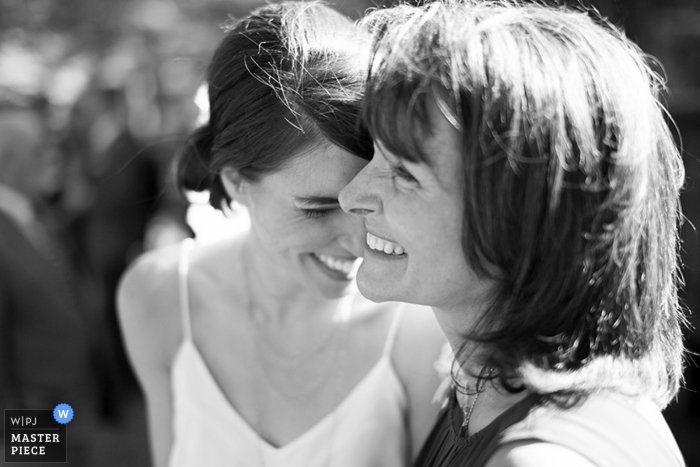 The bride smiles as she stands with another guest in this black and white photo composed by a documentary-style Hudson Valley, NY wedding photographer.