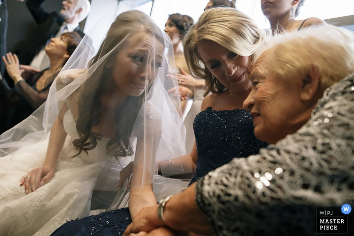 Manhattan wedding photographer captured this emotional image of a bride crying while holding the hand of her elderly grandmother