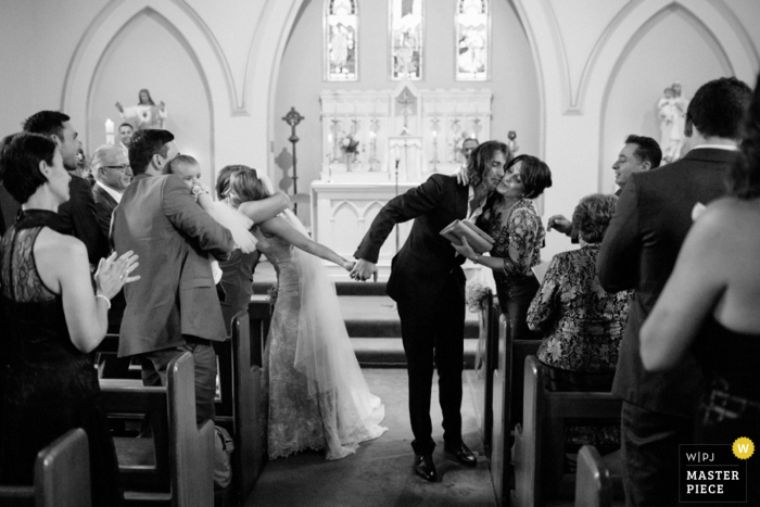 Gasten omhelzen de bruid en bruidegom bij het verlaten van de ceremonie in deze zwart-witfoto, gemaakt door een huwelijksfotograaf uit New South Wales, Australië.