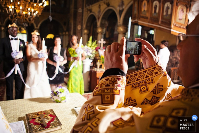 De priester maakt een foto van de bruid en bruidegom op deze bekroonde trouwfoto.