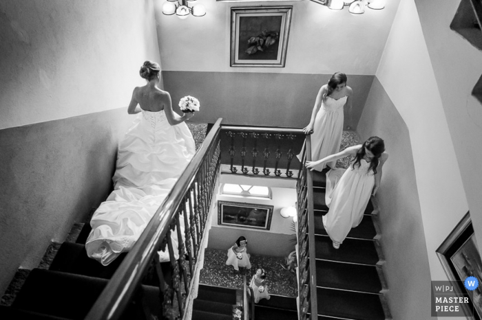 Foto door: <a href="https://www.wpja.com/contests/2015-q2-photography-contest/getting-ready/1634946"> Luigi Rota - Italië </a> De bruid en de bruidsmeisjes lopen onderaan een trap in deze zwart-witte foto door een de huwelijksfotograaf van Lombardije.