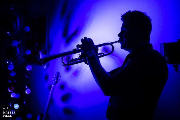 Offenburg wedding photographer captured this silhouette of a trumpet player as he plays at a blue lit reception