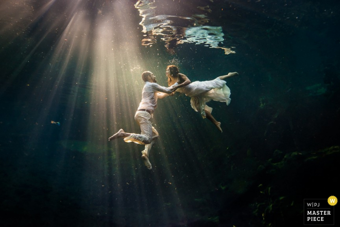 Photo by: <a href="https://www.wpja.com/contests/2015-q3-photography-contest/wildcard-portrait/1665556">Erik Shenko - Costa Rica</a> Cartago wedding photographer captured this underwater portrait of the bride and groom as they swim in streaks of sunlight