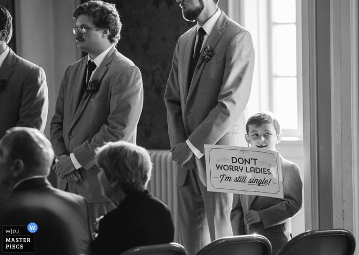 Niño de Omaha sostiene un cartel divertido en la boda - no se preocupen señoras, todavía estoy soltero - fotografía de bodas de Nebraska