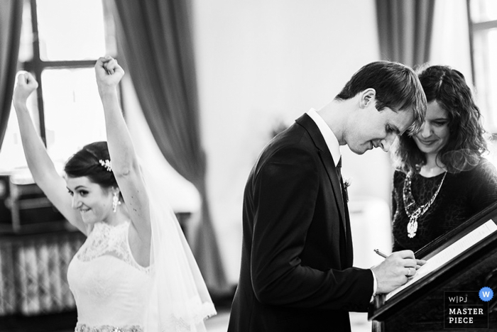 Belarus bride puts arms up in celebration during the ceremony - Europe wedding reportage photo