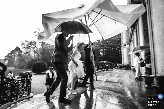 Photo by: <a href="https://www.wpja.com/contests/2015-q3-photography-contest/weather/1683771">Simon Cassanas - France</a> Paris man holds a huge umbrella for the bride outside in the rain - France wedding photo