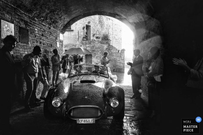 Photo by: <a href="https://www.wpja.com/contests/2015-q3-photography-contest/weather/1686226">Damiano Salvadori - Italy</a> Florence bride and groom leave the wedding in an old convertible car - Tuscany wedding photo in black-and-white