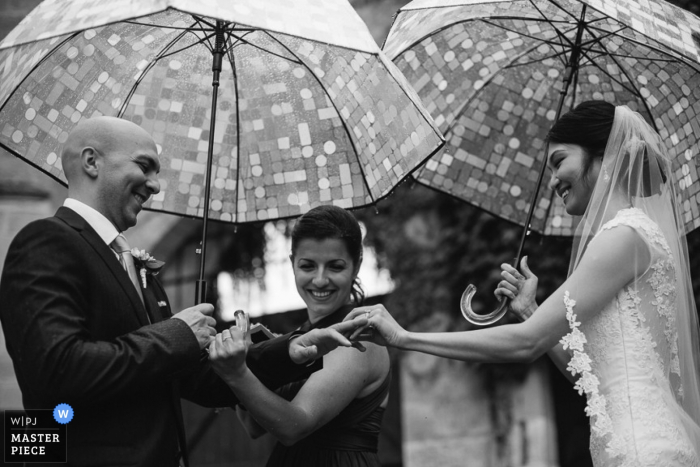 La novia y el novio de Nouvelle Aquitaine sostienen paraguas durante la ceremonia - Fotografía de boda en Francia