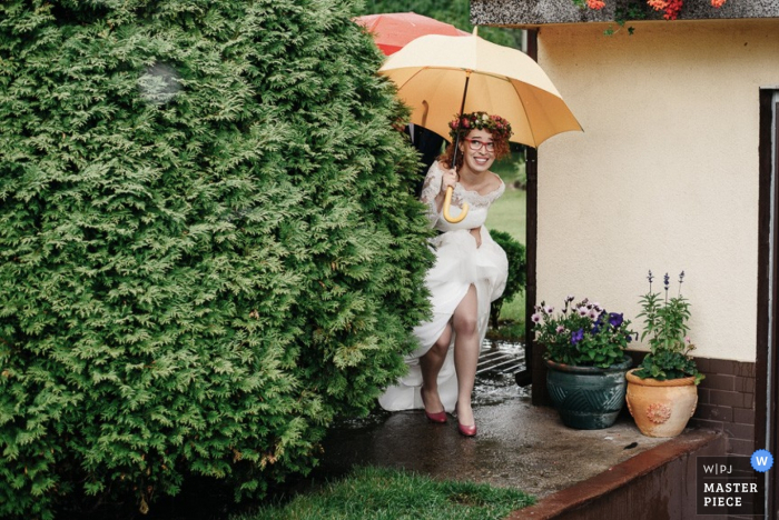 Novia de Varsovia corriendo para evitar la lluvia en su vestido - fotoperiodismo de bodas de Masovian