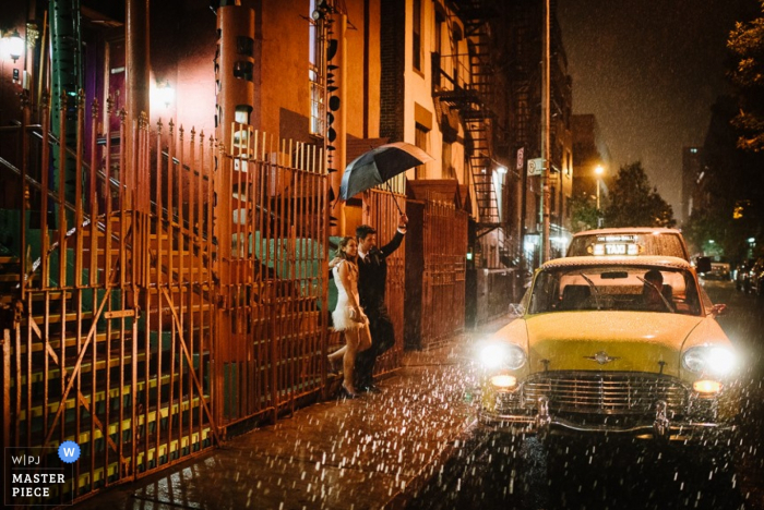 Manhattan bride and groom wait in the rain for a taxi - New York wedding photojournalism 