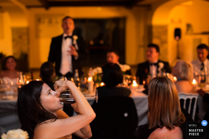 Foto por: <a href="https://www.wpja.com/contests/2015-q3-photography-contest/taste/1686241"> Damiano Salvadori - Italia </a> Invitado de Florencia tomando una copa mientras el novio habla en la recepción - Fotografía de boda en Toscana